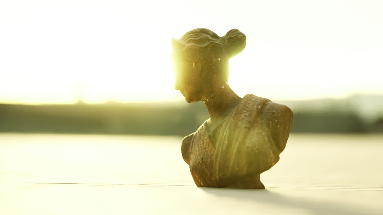 Sunlit bust sculpture forms a striking silhouette at sunset