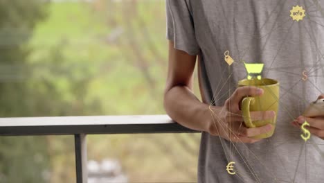 Globe-of-digital-icons-spinning-against-caucasian-man-with-coffee-cup-using-smartphone-at-home