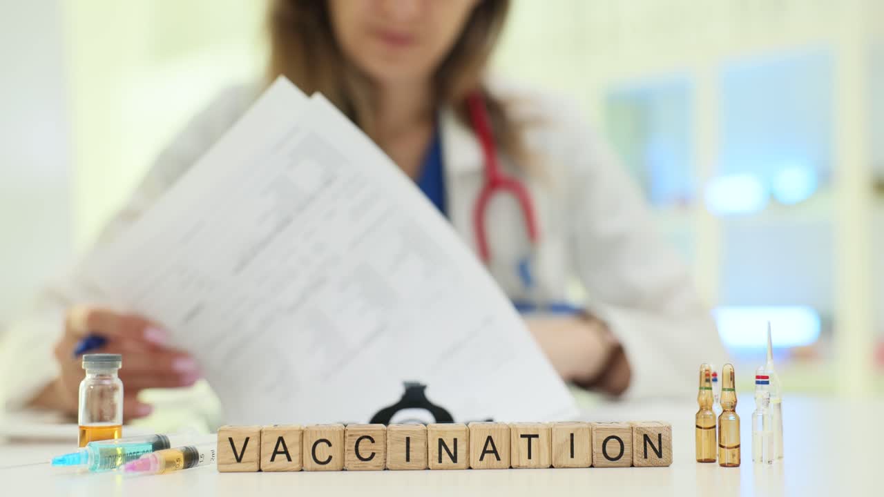 Doctor with Vaccination Supplies and Blocks Spelling 'Vaccination'