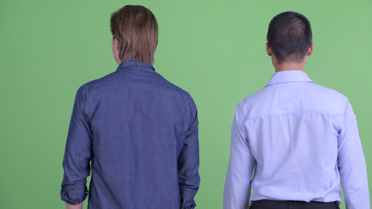 초록색 스튜디오 배경에 팔을 들고 흥분하고 행복해 보이는 두 사업가