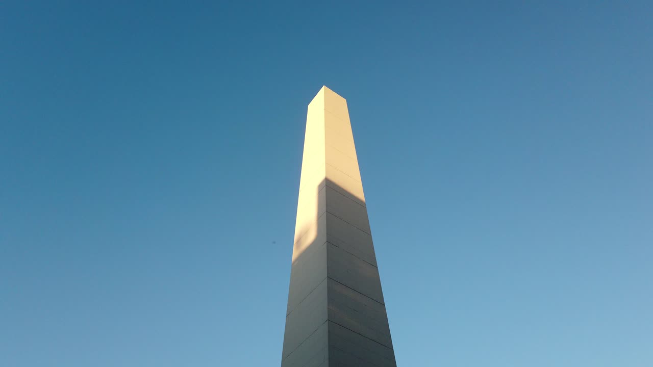 Wide angle tilt down along the Obelisk in Buenos Aires, a historic symbol of the city against blue sky