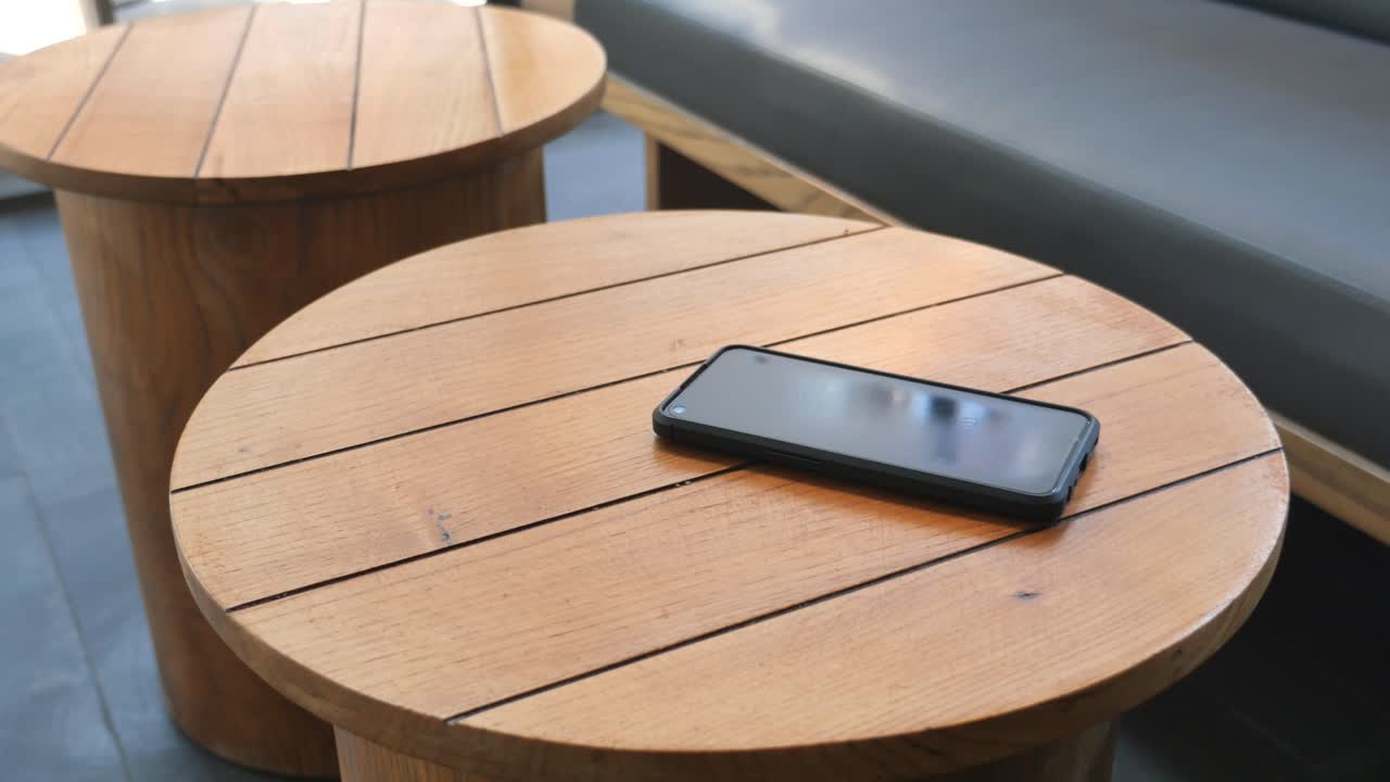 Hand Picking Up a Smartphone from a Wooden Table