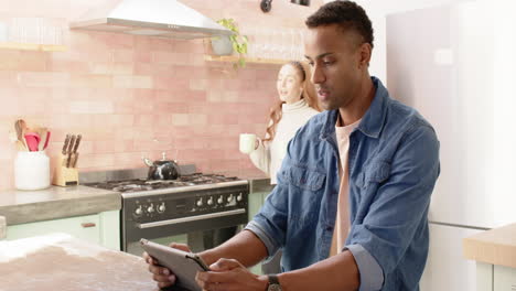 couple in kitchen enjoying coffee and looking at tablet, surprised and happy