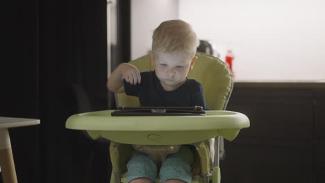 smart boy touches tablet screen opening app in high chair