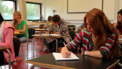 Estudiantes-Sentados-En-Un-Salón-De-Clases-Y-Tomando-Notas