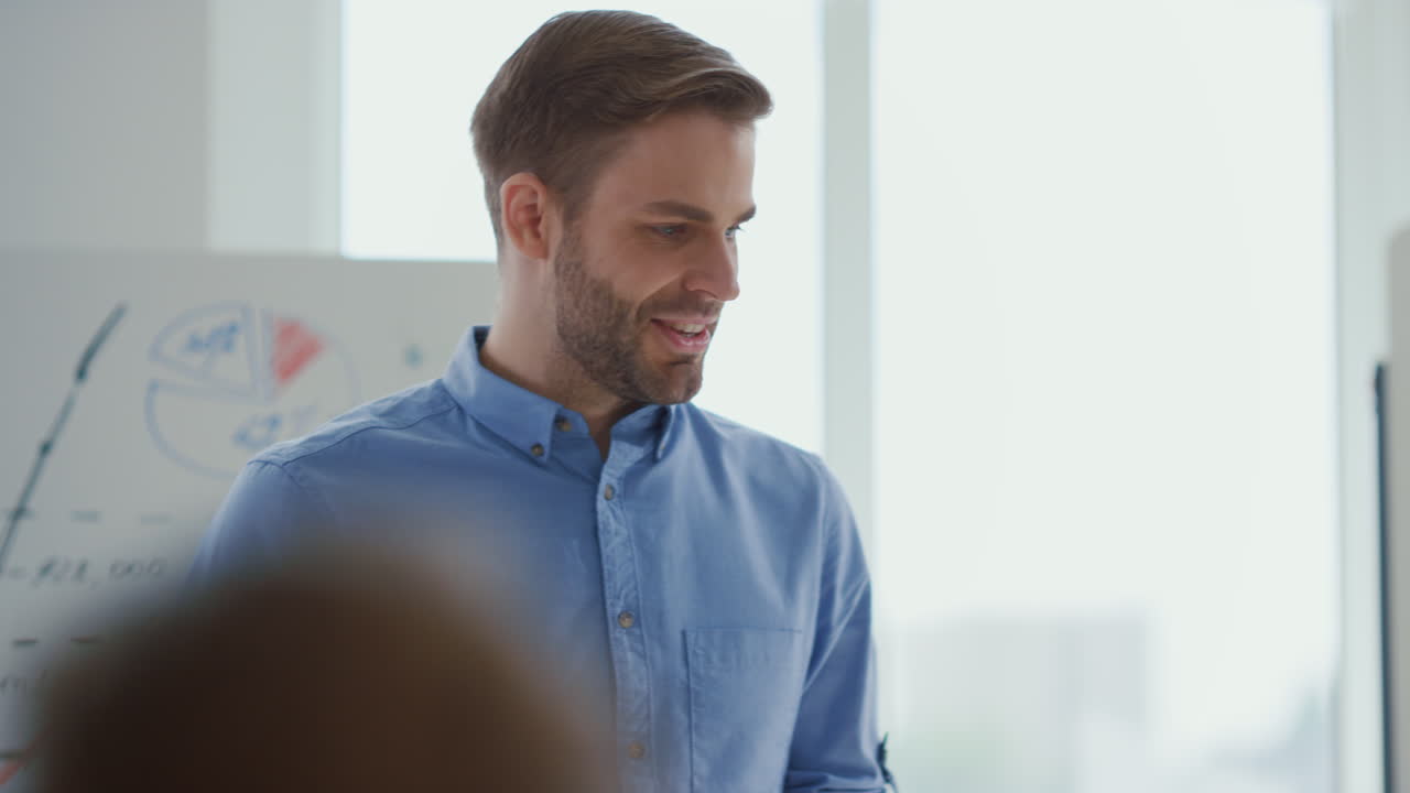 Confident man presenting startup office. Male speaker consulting team