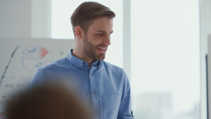 Confident man presenting startup office. Male speaker consulting team