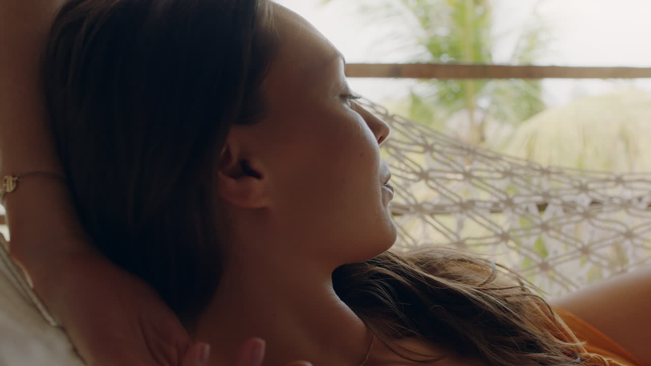 휴가 휴양지에서 휴가를 보내는 편안한 라이프 스타일을 즐기는 해마크에 있는 행복한 여성이 열대 천국 오두막에서 게으른 여름날에 평화롭게 흔들리고 있습니다.