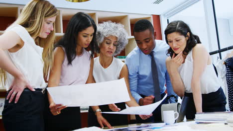 five colleagues discussing magazine production in an office