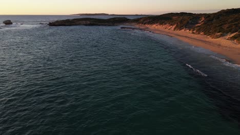 A-dynamic-high-angle-shot-of-the-shoreline-with-strong-waves-of-water-during-the-golden-hour