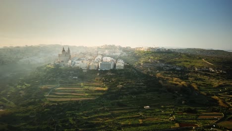 Drone-shot-pulling-away-from-Mellieha-Church-on-a-hill-in-a-heavily-misty-morning-in-Malta