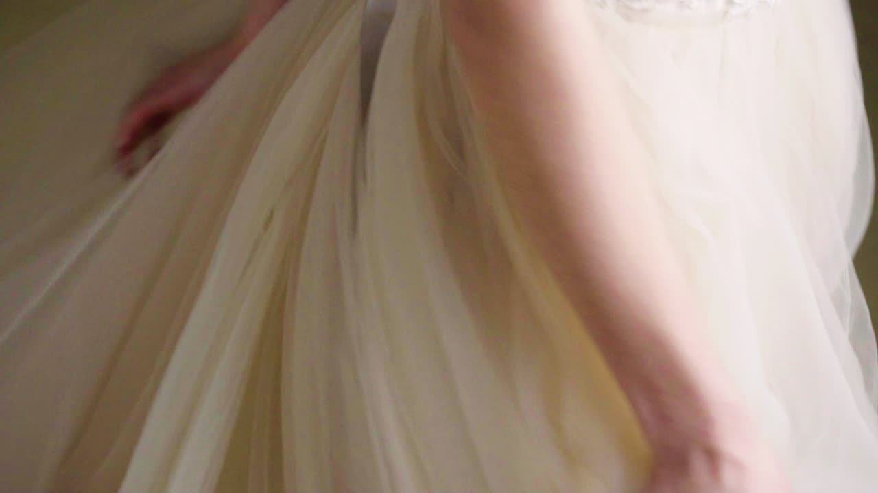 긴 저녁 드레스를 입은 젊은 갈색 여성이 카메라를 보고 돌아갑니다.