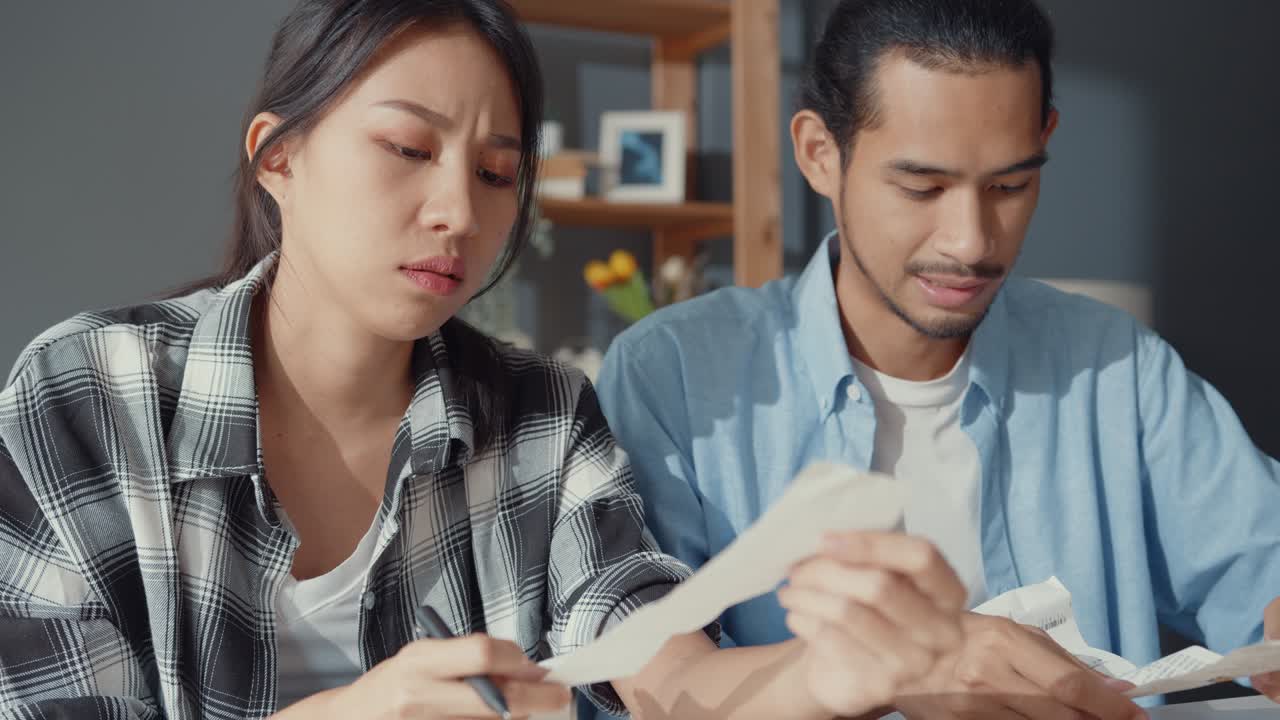 Stress asia couple man and woman use calculator for calculate family budget, debts, monthly expenses during financial economic crisis at home.