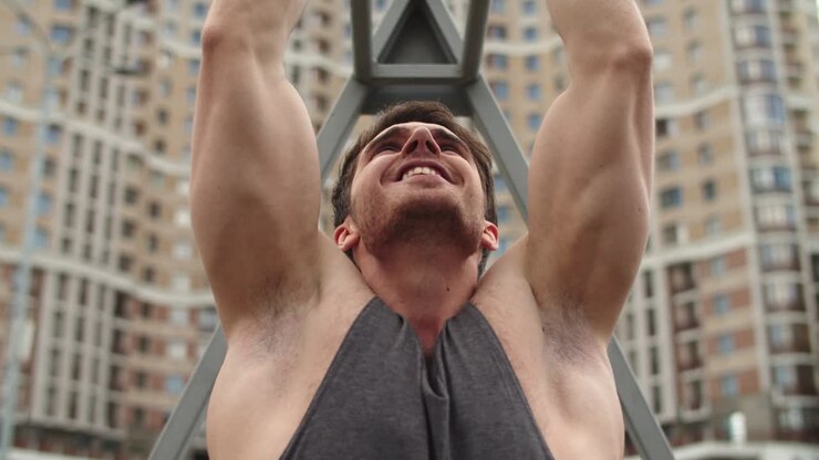 Close up of athlete man working out outdoor. Fitness guy doing pull ups
