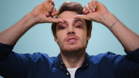 positive man making funny faces in studio. guy smiling on blue background