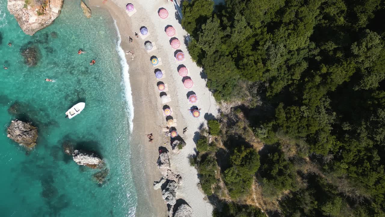 Drone quickly descends to multi colored colorful beach umbrellas on tropical sandy beach