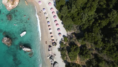 Drohne-Steigt-Schnell-Zu-Bunten-Sonnenschirmen-Am-Tropischen-Sandstrand-Hinab