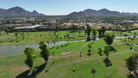 golf course with palm trees and mountains in background