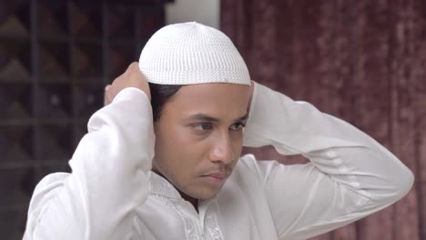 closeup of indian muslim man adjusting cap