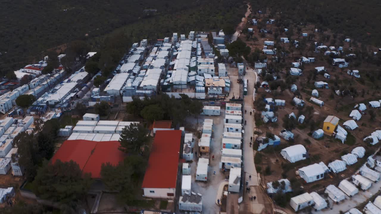 Aerial drone flight over moria refugee camp in Lesvos, Greece showing tents, containers and refugees in forest