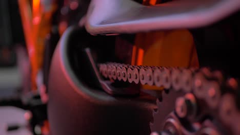 Close-Up-On-The-Chain-Of-An-Orange-KTM-Motorcycle-Superduke-1290-in-an-event-with-good-lights-and-bokeh