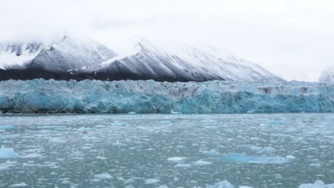 Blue-Blocks-of-Ice-in-front-of-a-glacier-with-mountains-as-a-backdrop