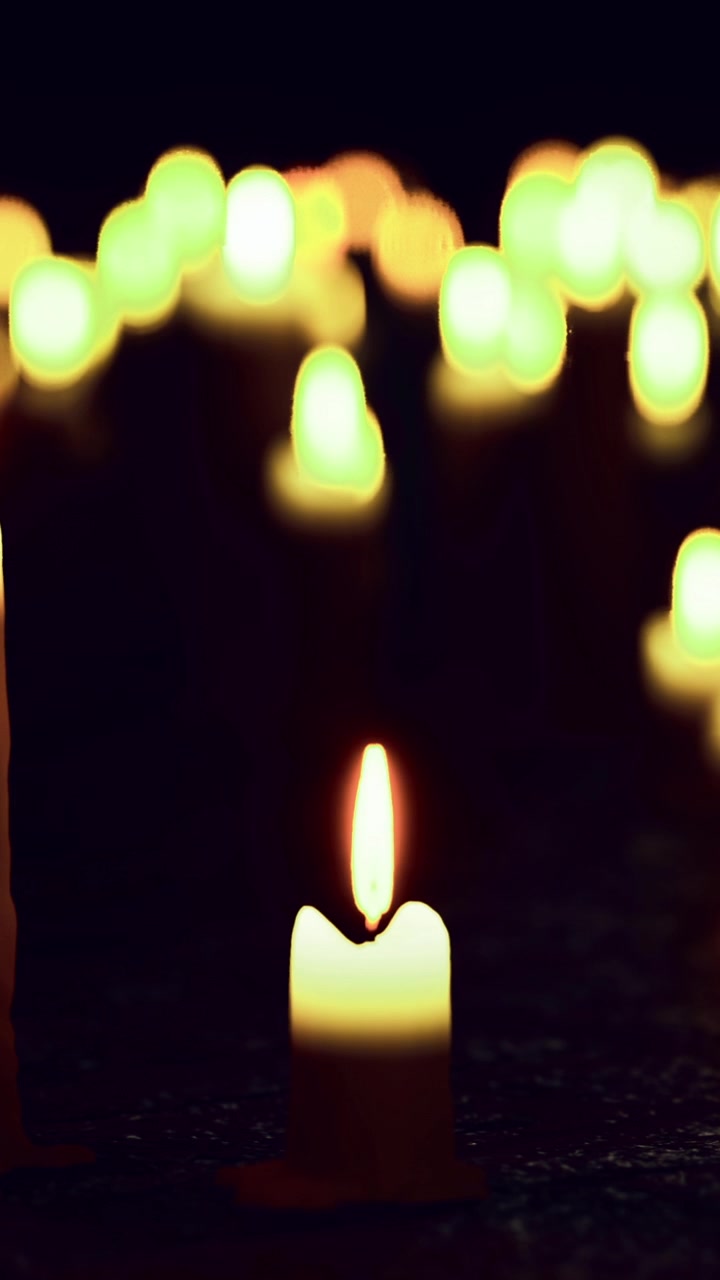 Molte candele con fiamme luminose in un ambiente buio durante un raduno.