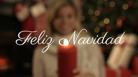 feliz navidad text animation over person holding red candle with christmas decorations