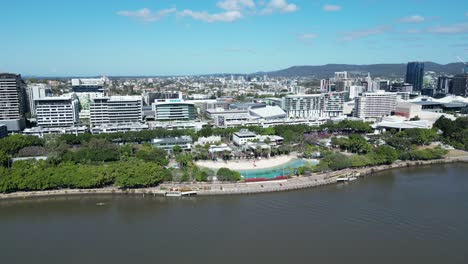 Imágenes-Aéreas-De-South-Bank,-South-Brisbane,-Tomadas-Al-Mediodía,-Con-La-Playa-De-South-Bank,-Zonas-Verdes-Y-El-Río-Brisbane.