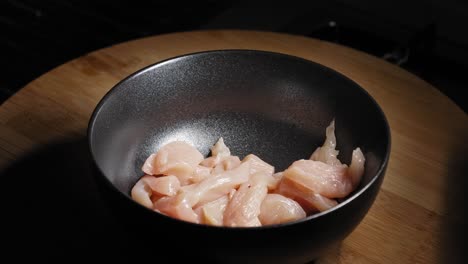 rebanadas de pechuga de pollo fresca cayendo en un tazón