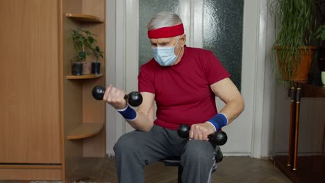 Senior-elderly-caucasian-man-making-weight-lifting-dumbbells-exercising-at-home-during-coronavirus