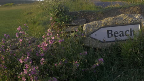 close up of sign on stone wall directing the way to british beach, panning shot