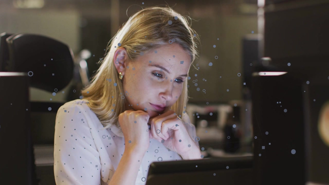 Woman sitting in dim business office, tapping tablet, causing floating particles, analyzing screen