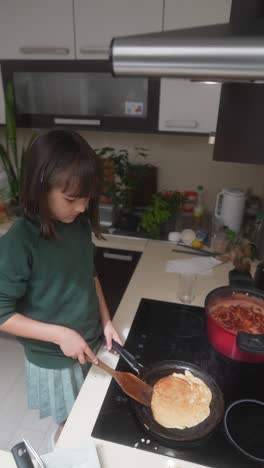 young girl cooking pancakes
