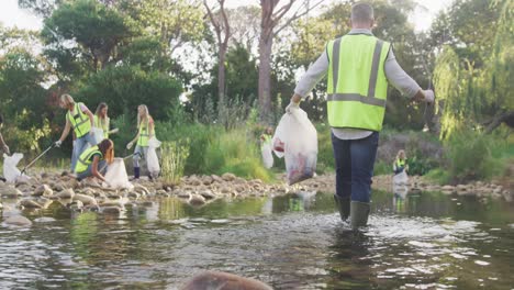 adultos de mediana edad con chalecos amarillos voluntarios durante el día de limpieza del río