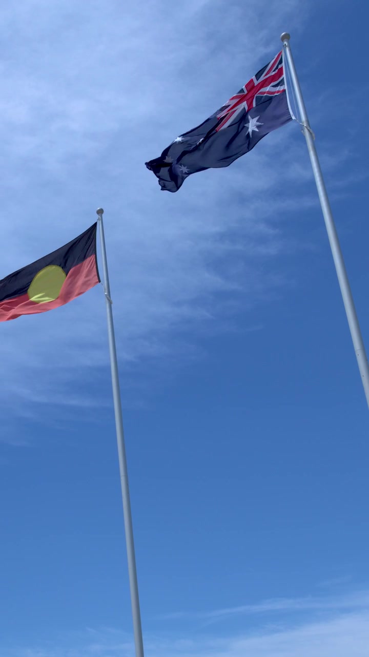 Low angle shot of Australian, Aboriginal, and Torres Strait Islander flags waving against blue sky