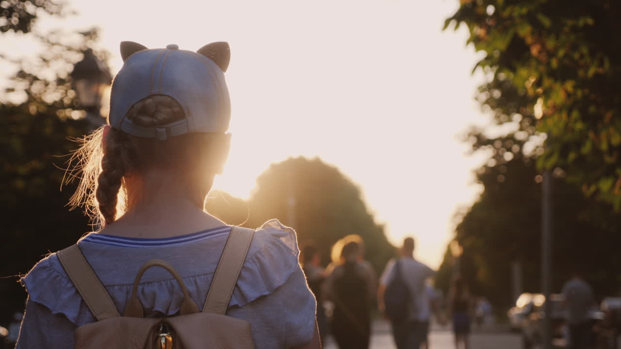 배낭을 메고 있는 소녀가 지나가는 도시 공원에 있다