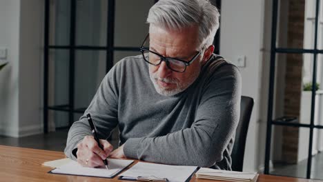 experienced executive carefully signing legal papers, reviewing corporate documents with intense focus while working at modern office desk, displaying professional concentration