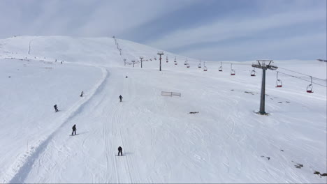 Drone-view-of-skiers-skiing-downhill-in-the-slopes-in-the-scenic-Mountain-Kaimaktsalan-Greece-winter-day