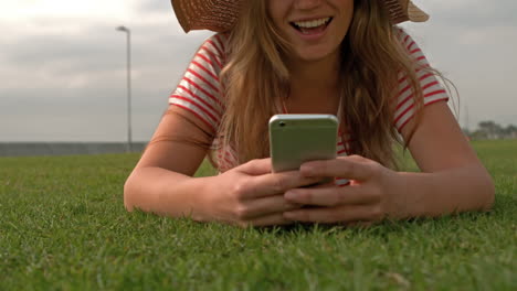 Mujer-Sonriente-Usando-Un-Teléfono-Inteligente-En-El-Parque