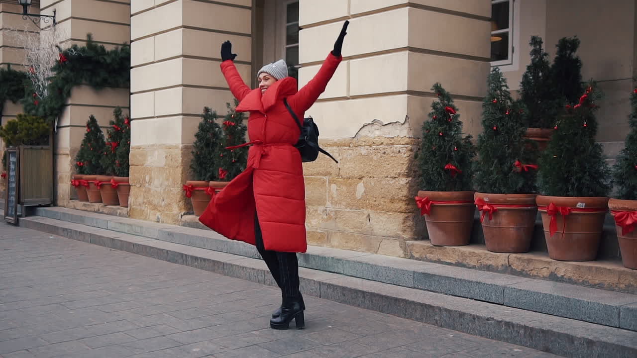 Woman in Red Coat on City Street with Christmas Decorations