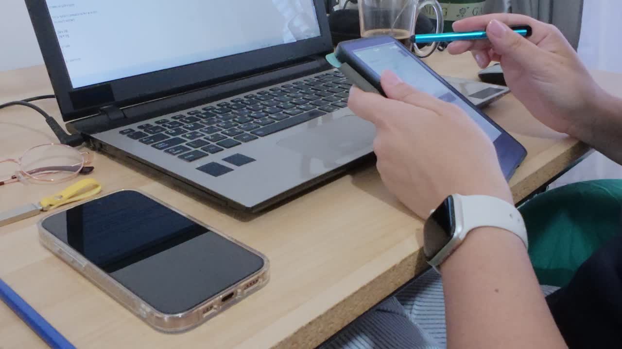 Professional using a tablet for documents or presentations, working concurrently on a laptop.