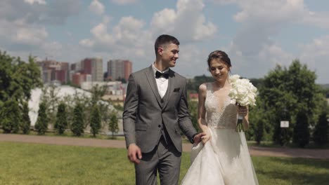 Lovely-newlyweds-caucasian-bride-groom-running-in-park,-holding-hands,-wedding-couple-family