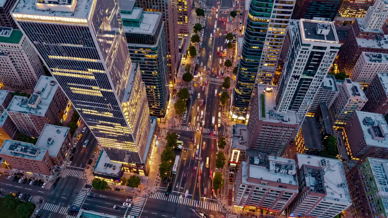 Aerial view of a bustling city intersection at dusk, showcasing vibrant lights and dynamic movement