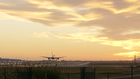 toma panorámica lenta a la derecha del aterrizaje de un avión comercial en el aeropuerto de barcelona al atardecer