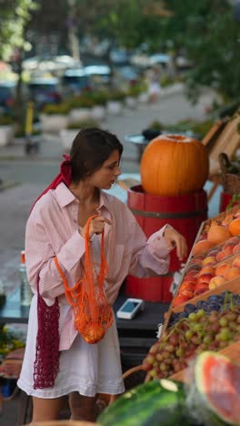 woman shopping for fresh fruit at an outdoor market