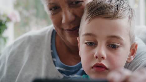 kleiner junge benutzt smartphone mit großmutter, hat video-chat, winkt bei der familie, teilt urlaubswochenende mit großmutter, chattet am handy, entspannt sich zu hause mit enkel 4k