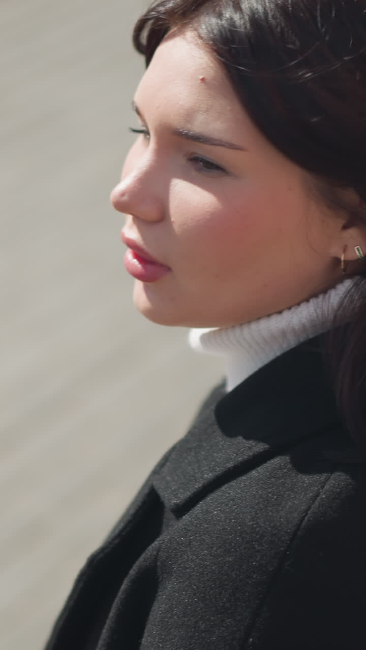 Close-up of woman turning her head to the side, brown hair flowing with movement, eyes focused ahead, background features a blurred object near her