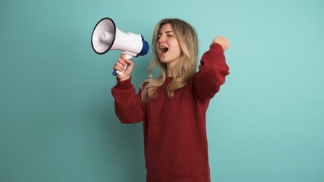 young woman protesting with megaphone in blue studio
