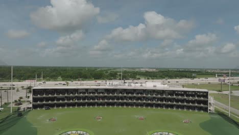 aerial view of a topgolf driving range facility next to a highway under a cloudy sky